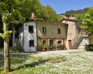 an old stone house with flowers in front of it at Il Molino Di Serravalle in Bibbiena