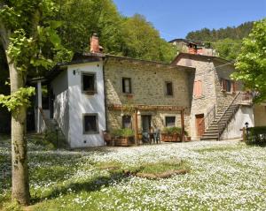 une ancienne maison en pierre avec des fleurs devant elle dans l'établissement Il Molino Di Serravalle, à Bibbiena
