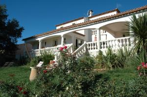 uma casa branca com um alpendre e algumas flores em Villa Chiara em Magalas