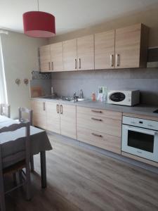 a kitchen with wooden cabinets and a white microwave at Gîte Pierre et Marie in Mellecey