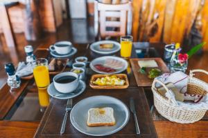 a wooden table with breakfast foods and drinks on it at Vaihu Nui Bungalow-Glamping in Hanga Roa +33 photos