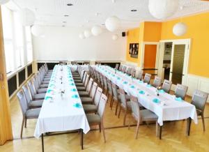 - une grande table avec des tables et des chaises blanches dans la chambre dans l'établissement Sporthotel Glück Auf Mönchenfrei, à Brand-Erbisdorf