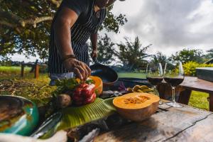 a person preparing food on a picnic table with wine glasses at Vaihu Nui Bungalow-Glamping in Hanga Roa