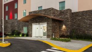 a building with a white door and a brick wall at Candlewood Suites - Queretaro Juriquilla by IHG in Querétaro