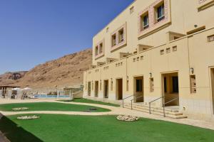 a building with a green lawn in front of it at HI - Massada Hostel in Ein Bokek