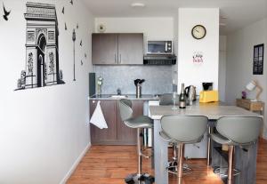 a kitchen with a counter and stools in a room at Studio Confort Paris in Montévrain