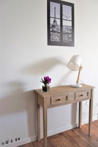 a wooden table with a lamp and flowers on it at Studio Confort Paris in Montévrain