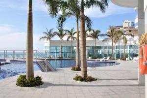 a swimming pool with palm trees and a building at Apartamentos Palmeto Cartagena Nª3401 in Cartagena de Indias