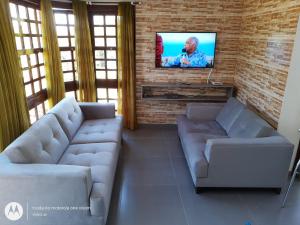 uma sala de estar com 2 sofás e uma televisão de ecrã plano em Vista Real Residence em Gramado