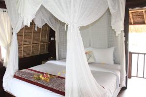 two beds in a room with white drapes at MolaMola House in Nusa Lembongan