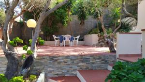 een patio met stoelen en bomen in een tuin bij Casa Vacanza Marco in La Maddalena