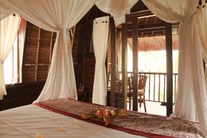 a bedroom with a bed with white curtains and a balcony at MolaMola House in Nusa Lembongan +69 photos
