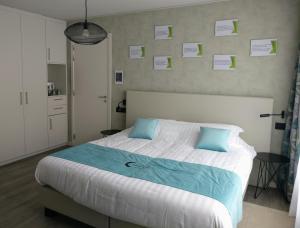 a bedroom with a large bed with blue pillows at B & B De Veurnse Slaper in Veurne