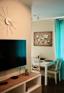 a living room with a large television and a table at Neptune Ear, Family-friendly, modern, fully-equipped, cozy apartment in Ventspils