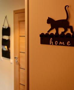 un gato negro sentado encima de un cartel en una puerta en Neptune Ear, Family-friendly, modern, fully-equipped, cozy apartment en Ventspils