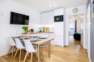 a kitchen and dining room with a table and chairs at Apartament 4B Blue Marine Poddąbie in Poddąbie