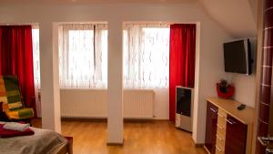 una camera con due finestre con tende rosse di Mary Apartment a Sibiu