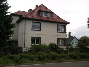 une maison blanche avec un toit rouge et une clôture dans l'établissement Pension-Nussbaum, à Grünewalde