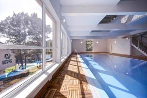 a large swimming pool in a building with a large window at Apartament 12B Blue Marine Poddąbie in Poddąbie