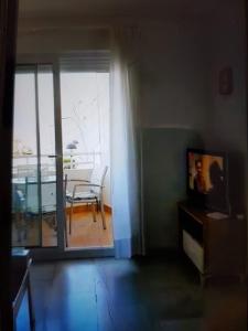 a living room with a tv and a table and a balcony at Apartamento primera linea junto al puerto in Denia