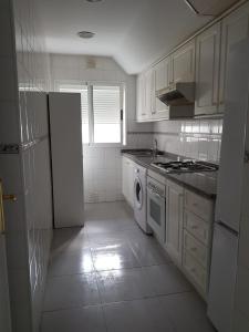 a kitchen with a white refrigerator and a dishwasher at Apartamento primera linea junto al puerto in Denia