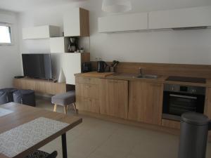 cocina con armarios de madera, fregadero y mesa en Georges Beach Appart, en Wimereux