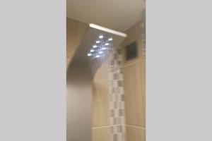 ein Bad mit einer Dusche mit Licht an der Wand in der Unterkunft Appartement 2 chambres Angers Centre de Congrès in Angers