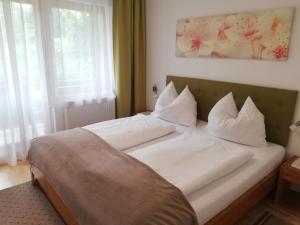 uma cama com lençóis brancos e almofadas num quarto em Ferienwohnungen Vidoni em Bodensdorf