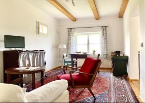 ein Wohnzimmer mit einem Sofa und einem roten Stuhl in der Unterkunft Historischer Pfarrhof Niederleierndorf in Langquaid