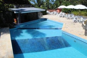 Una piscina azul con sillas y sombrilla. en Casa da Uba Una, en Ubatuba 35 fotos más