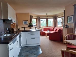 kuchnia i salon z czerwoną kanapą w obiekcie Appartementhaus St. Martin w mieście Seefeld in Tirol