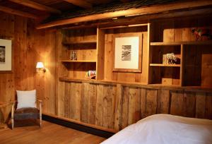 Gîte de Planchouet في نينداز: غرفة نوم بجدران خشبية وسرير وكرسي
