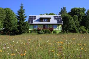 a house with solar panels on its roof in a field at Maślana Chata in Sokolec