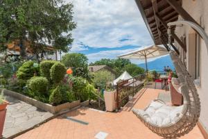 eine Veranda mit einem Schaukelstuhl und einem Sonnenschirm in der Unterkunft Casa Heli I in San Zeno di Montagna