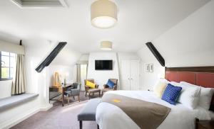 a bedroom with a bed and a desk and chairs at voco Oxford Thames by IHG in Oxford