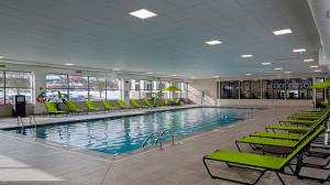 a large swimming pool with green chairs in a building at Candlewood Suites - Cleveland South - Independence by IHG in Independence