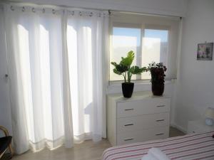 a bedroom with a window with white curtains and a dresser at 9 Avenue de Carras in Nice