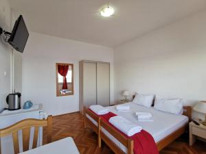Un dormitorio con una cama grande con sábanas blancas y una mesa. en Rooms Ante en Tribanj-Krušćica
