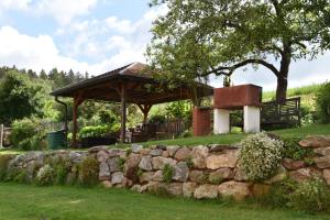 um gazebo num campo com uma parede de pedra em Villa Rosa em Pfreimd