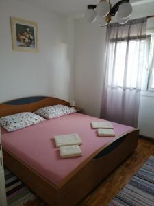 a bedroom with a pink bed with towels on it at Apartman Sunce in Ogulin