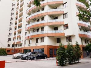 un gran edificio de apartamentos con coches aparcados frente a él en Palas Studios en Iaşi