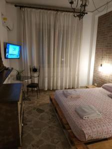 um quarto com uma cama, uma secretária e uma televisão em Tilde B&B em Cefalù