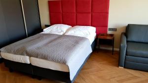 Apartament Wrocław Marina nad Odrą 29 في فروتسواف: غرفة نوم مع سرير مع اللوح الأمامي الأحمر وكرسي