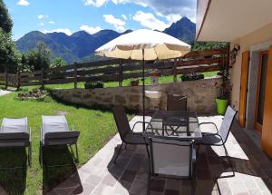 a patio with a table and chairs and an umbrella at Ledro Nest in Ledro