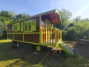 une voiture de train verte garée dans l'herbe dans l'établissement Les Roulottes de La Ferme Chauvet, à Chantenay-Villedieu