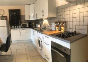 a kitchen with white cabinets and a stove top oven at Gîte Au Coeur Du Pays Cathare in Fanjeaux