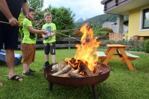 two boys playing with a fire in a grill at Appartement Mama in Haus im Ennstal