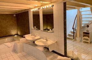 La salle de bains est pourvue de 2 lavabos et d'une baignoire. dans l'établissement L'Hôtel by Hostellerie du Château, à Rolle