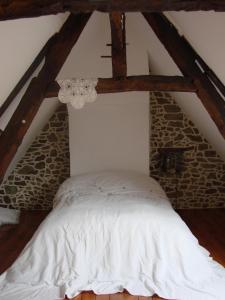 朗巴勒的住宿－CHAMBRE ROMANTIQUE CHEZ L'HABITANT à LAMBALLE，阁楼内的白色床,设有石墙