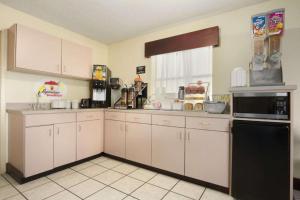 a kitchen with white cabinets and a black microwave at Super 8 by Wyndham Monroe in Monroe
